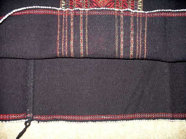 56K Jpeg Mru B02 Mru woman's tubeskirt from Bangladesh where the Mru live in the Chittagong Hill Tracts in the borderland between Burma, Inda and Bangladesh. The photo detail  shows the reverse, inner side of the woven skirt with the top part being the reverse of the red woven band and the bottom showing the fell seam join. 