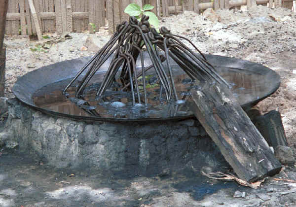 The dye vat with hanks of cotton held over iron hooks soaking in the dye and wood for burning in the foreground - Amarapura, Shan State 9809f07.jpg