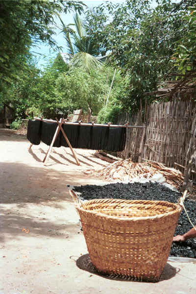 Hanks of dyed cotton hanging out to dry with charcoal, a bi-product of the dyeing process spread out in front to dry  - Amarapura, Shan State 9809f16.jpg