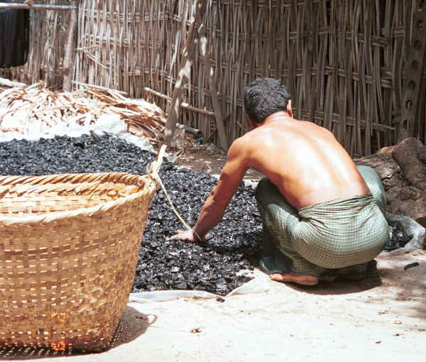 One of the dyers spreading out to dry the charcoal which is a bi-product of the dyeing process - Amarapura, Shan State 9809f17.jpg