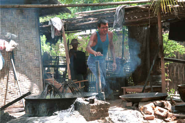 The head of the family of dyers blowing up the fire under the dye bath - Amarapura, Shan State 9809f18.jpg