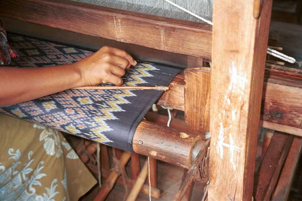 Jpeg 40K 9809O29 A three colour ikat being woven on a loom in the weaving mill at Innbawkon (Inpawkhon) on Lake Inle, Shan State. Note the tensioning 'bow' fixed across the width (weft) of the woven fabric to keep the tension and width constant.