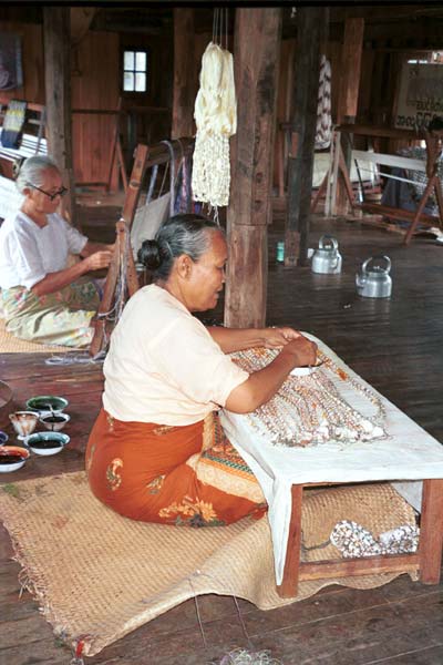 Jpeg 43K 9809O33 The ikat preparation process at a weaving mill at Innbawkon (Inpawkhon) on Lake Inle, Shan State: an Intha woman painting on the first dye in the ikat process; in the background another ties off the resists in the silk prior to dyeing.