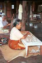 to Jpeg 43K 9809O33 The ikat preparation process at a weaving mill at Innbawkon (Inpawkhon) on Lake Inle, Shan State: an Intha woman painting on the first dye in the ikat process; in the background another ties off the resists in the silk prior to dyeing.