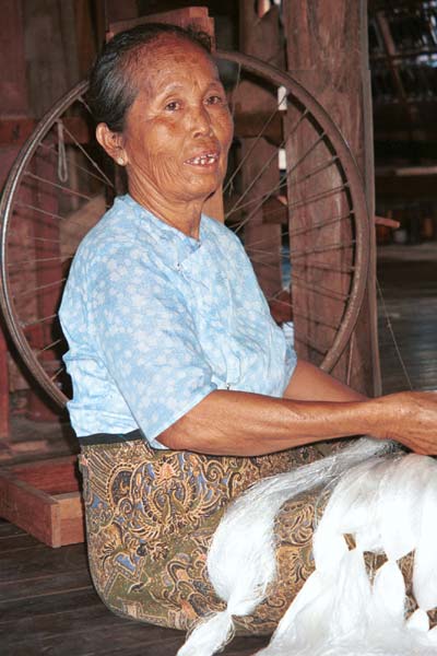 40K Jpeg 9809P02AE Intha woman with skeins of silk threads in her lap as she works on the early preparation stages of the threads in the ikat process at a weaving mill at Innbawkon (Inpawkhon) on Lake Inle, Shan State.