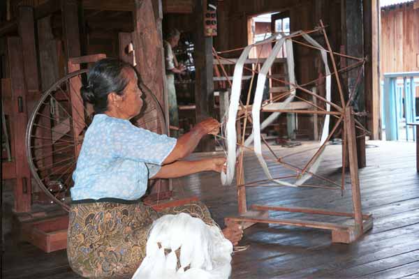 31K Jpeg 9809P04E Intha woman with skeins of silk threads in her lap as she works on the early preparation stages of the threads in the ikat process at a weaving mill at Innbawkon (Inpawkhon) on Lake Inle, Shan State.