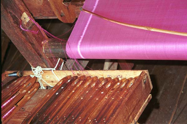 Jpeg 39K 9809P13 Width plain silk weaving in between lengths of ikat with a container of weft shuttles carefully in order for the ikat pattern sections. All at a weaving mill at Innbawkon (Inpawkhon) on Lake Inle, Shan State.