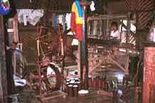 to Jpeg 41K 9809R13 Winding the spools and weaving cloth for monks' clothing in a house off a waterway at the back of the floating market at Ywa-ma- Lake Inle, Shan State.