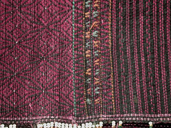 Jpeg 60K Khumi woman's tubeskirt - detail showing the black warp and red supplementary weft patterning to the left and red and black stripes of supplementary weft to the right