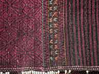 to Jpeg 60K Khumi woman's tubeskirt - detail showing the black warp and red supplementary weft patterning to the left and red and black stripes of supplementary weft to the right