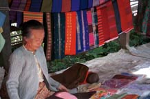 to Jpeg 55K Woman selling woven textiles in Kalaw 5 day rotating market, Shan State. There would appear to be some Silver Palaung woven striped tubeskirts hanging to the right of the photo.