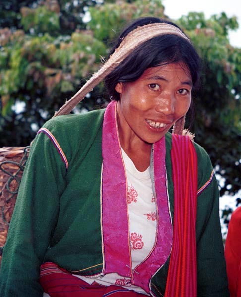 74K Jpeg Silver Palaung woman carrying the weight of a heavy basket on her head in the hills near to Kalaw. It is interesting to note that she has used a deep pink satin brocade for the wide edging around the front and neck of her blouse.