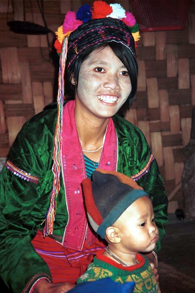 69K Jpeg A Silver Palaung woman and her young child in Pein Ne Bin village near Kalaw, northwestern Shan State. He is wearing a hat made of what appears to be felted fabric in different colours. His mother is wearing a cap usually worn young girls and unmarried women. The fabric in her blouse is typical of the shiny, velour fabrics which are currently popular. Note the embroidered seams where the sleeves are set into the blouse and which are also decorated with sequins.