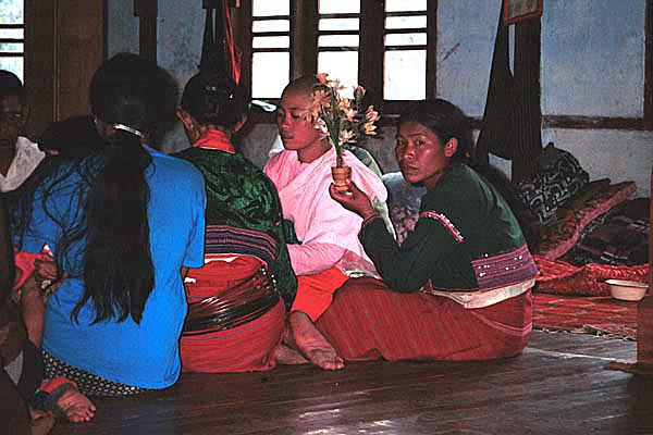 66K Jpeg Silver Palaung women gathering together to pray in the Buddhist temple in the centre of Pein Ne Bin village near Kalaw, northwestern Shan State on 'Full Moon Day' after the night of the full moon. Note the two women in traditional woven skirts, decorated bloues and the woman on the left of centre wearing bamboo or rattan hoops around her waist.