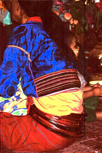 90K Jpeg A Silver Palaung woman in the Buddhist temple at Pein Ne Bin village near Kalaw, northwestern Shan State joining in the prayers on the day after the full moon 'Full Moon Day". She is wearing a traditional hand woven skirt, embroidered shiny velvet blouse and the Silver Palaung identifying bamboo or rattan hoops. 