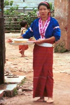 to 75K Jpeg Silver Palaung woman wearing the traditional hand woven tube skirt and decorated blouse carrying food utensils back from the communal meal for the 'Full Moon day' festival