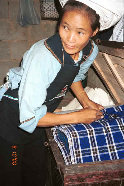 Bouyei woman looking in her fabric storage chest - Bi Ke village, Mi Gu township, Zhenfeng county, Guizhou province 0010r34.jpg