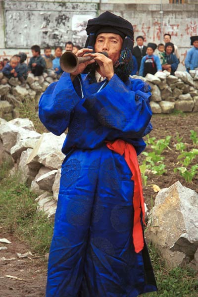 Jpeg 51K 0110D15  Trumpeter blowing his welcome to Gan He village, Ya Rong township, Huishui county, Guizhou province, south-west China. Note the complex weaving of the ends of his head-cloth. The people living in this village are known as Qing Miao. There has been much intermarriage between Miao and Bouyei which is evident from the costume of the women.