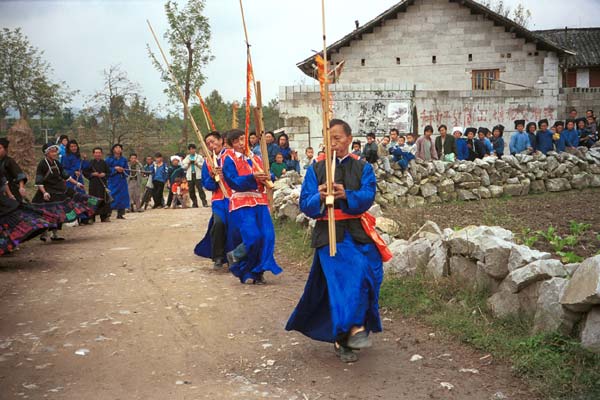 Jpeg 52K  0110D25 Villagers welcoming us to Gan He village, Ya Rong township, Huishui county, Guizhou province, south-west China. Musicians led by men playing on large lusheng pipes. The people living in this village are known as Qing Miao. There has been much intermarriage between Miao and Bouyei which is evident from the costume of the women. 