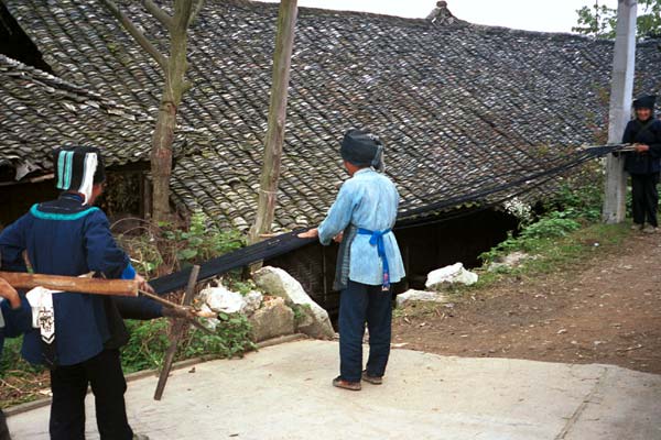 Jpeg 57K  0110E14 Three women untangling and straightening up the indigo warp threads before warping up a loom in Gan He village, Ya Rong township, Huishui county, Guizhou province. This is a Qing Miao (or Bouyei/Miao as there has been much intermarriage and the costume is very mixed).