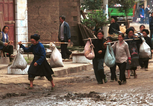 Jpeg 87K Miao women trying to avoid the mud as they carry their produce down the main street in Bai Jin township, Huishui county, Guizhou province 0110C02