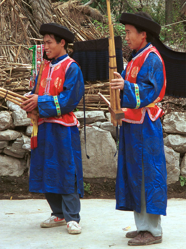 Jpeg 165K Lusheng musicians waiting to play against a backdrop of woven, striped indigo skirts, Gao Zhai village, Bai Jin township, Huishui county, Guizhou province 0110C10