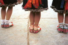 to Jpeg 58K Back view of Iron beating Miao women whilst they dance showing their embroidered shoes, Gao Zhai village, Bai Jin township, Huishui county, Guizhou province. Unfortunately it is becoming unusual to still see hand made shoes rather than ubiquitous trainers on the dancers' feet 0110C13