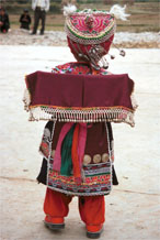 to Jpeg 129K Iron beating Miao festival costume in miniature worn by one of little girls who danced for us in Gao Zhai village, Bai Jin township, Huishui county, Guizhou province. She is wearing what looks like a very ornate baby carrier on her back 0110C15