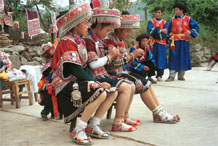 to Jpeg 138K Iron beating Miao women in Gao Zhai village, Bai Jin township, Huishui county, Guizhou province working on some embroidery and wearing their festival finery watched by the musicians 0110C28