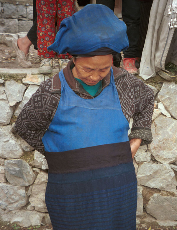 Jpeg 125K Iron beating Miao woman showing me how the finely pleated, woven striped indigo dyed skirt is worn. I have just bought this skirt from her. Her husband had sent her into her house to fetch me a finer one when I had found some mildew on one which she had out for sale. Gao Zhai village, Bai Jin township, Huishui county, Guizhou province 0110D09