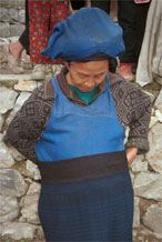 to Jpeg 125K Iron beating Miao woman showing me how the finely pleated, woven striped indigo dyed skirt is worn. I have just bought this skirt from her. Her husband had sent her into her house to fetch me a finer one when I had found some mildew on one which she had out for sale. Gao Zhai village, Bai Jin township, Huishui county, Guizhou province 0110D09