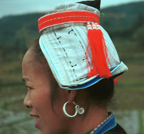 Jpeg 46K 0100F30 Gejia woman showing her headdress. The fabric is a machine printed reproduction of a traditional Gejia wax resist design. All the women in this village seemed to be wearing the commercially printed fabric and we did not see any original wax resist being worn on headdresses. Ma Tang village, Kaili City, Guizhou province.