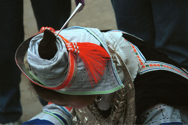 Jpeg 57K 0111 A Gejia woman showing her headdress and part of her jewlery. The fabric is commercially printed to imitate the traditional wax resist designs of the Gejia. Ma Tang village, Kaili City, Guizhou province