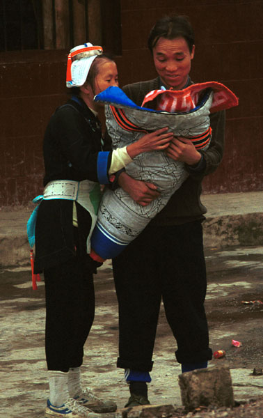 Jpeg 53K 0111G28 A Gejia couple loving their baby which is wrapped in a winter wax resist baby carrier. Ma Tang village, Kaili City, Guizhou province.