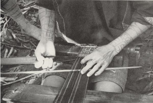 to Jpeg 52K A close up of a Ba-sa-dung woman weaving one of the narrow bands which will be sewn together to make her short tubeskirt.  It is amazing that the very complex designs which are created by these Li women are achieved on such simple looms. The photo comes from the article in the September 1938 National Geographic by Leonard Clark telling of his 5-week trek into the interior of Hainan in the summer of 1937.