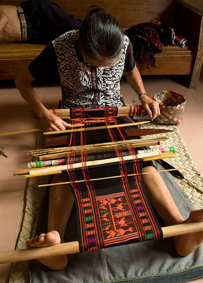 Weaver Huang Ji Xiang, who is a member of the Qi subgroup of the Li people, making the cloth that is called "Li brocade" locally. This particular cloth is for the tourist market, rather gaudy and with large, widely spaced designs (probably for ease and speed of production), but Chris thinks that the basic technique is the same used to make most Li minority supplementary weft weavings. 