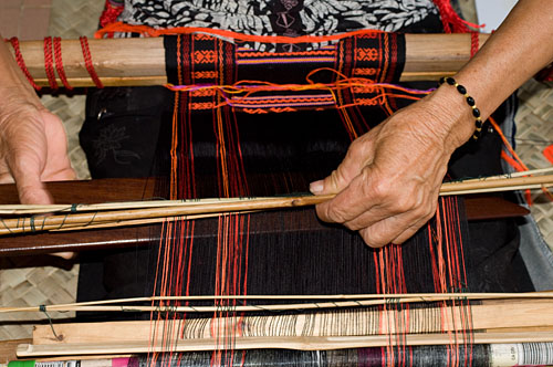 Weaver Huang Ji Xiang (01), who is a member of the Qi subgroup of the Li people, making the cloth that is called "Li brocade" locally. Weaving proceeds via two separate sheds. A lower shed is opened with the large, dark colored weaving sword. 