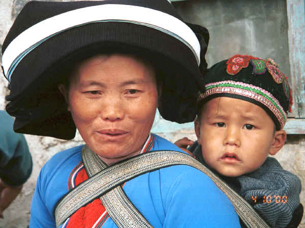 Side comb woman and child showing baby carrier straps of batik and boy wearing his embroidered cap - Long Dong village, De Wo township, Longlin country, Guangxi province 0010f10.jpg