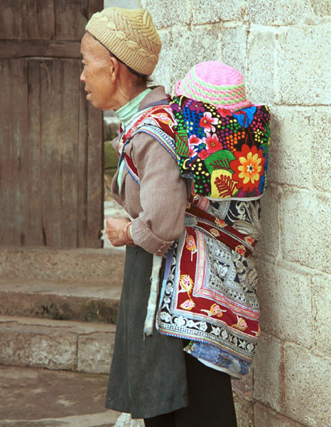 Jpeg 100K Miao woman with baby in waxed (batik) and embroidered baby carrier in Lou Jia Zhuang village, Anshun city, Guizhou province 0110B03