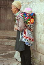 to Jpeg 100K Miao woman with baby in waxed (batik) and embroidered baby carrier in Lou Jia Zhuang village, Anshun city, Guizhou province 0110B03