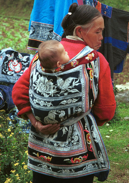 Jpeg 107K Miao woman with baby in waxed (batik) and embroidered baby carrier in Lou Jia Zhuang village, Anshun city, Guizhou province 0110B04