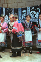 to Jpeg 116K Group of Miao women wearing a mixture of clothing including wax resist (batik) and embroidery. The traditional costume has absorbed styles from other Miao as well as other influences. Note the traditional festival hair styles of some of the women. Lou Jia Zhuang village, Anshun city, Guizhou province 0110B12a