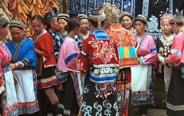 Jpeg 111K Group of Miao women wearing a mixture of clothing including wax resist (batik) and embroidery. The traditional costume has absorbed styles from other Miao as well as other influences. Note the traditional festival hair styles of some of the women. Lou Jia Zhuang village, Anshun city, Guizhou province 0110B12b