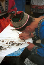 to Jpeg 73K Miao woman wearing festival costume and hair style using her la dio (literally 'wax knife') to apply the wax resist la ran (literally 'wax dye') in a floral style. Lou Jia Zhuang village, Anshun city, Guizhou province 0110B19