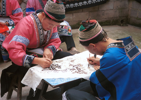 Jpeg 81K Two Miao women wearing their festival costumesworking on wax resist (batik) in the floral style which may the reason for their nickname 'Flower Miao'. Note the front and back of their traditional hair styles. Lou Jia Zhuang village, Anshun city, Guizhou province 0110B24