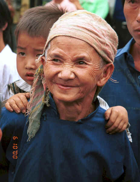 Old White Miao lady, probably with her grandson on her back and her son behind her in the crowd to welcome us to Ma Wo village, Zhe Lang township, Longlin county, Guangxi province 0010j03.jpg