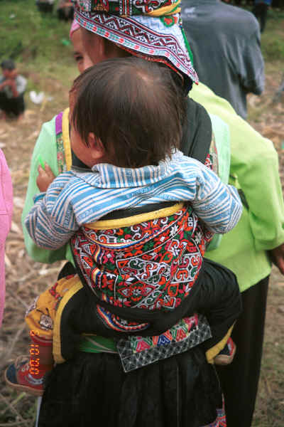 White Miao baby held in an embroidered  baby carrier, Ma Wo village, Zhe Lang township, Longlin county, Guangxi province 0010k09.jpg