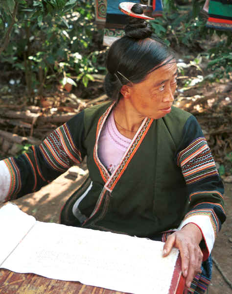 Side Comb Miao married woman about to start waxing a piece of batik.  Note her hairstyle which gives the group its Han nickname and how the continual twisting of the hair into a tight knot into which the comb is placed is causing some baldness. Pao Ma Cheng village, Teng Jiao township, Xingren country, Guizhou province. 0010n23.jpg