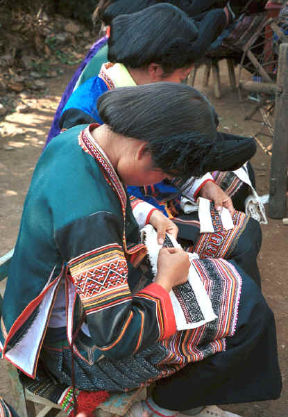 Side Comb Miao girls dressed their festival finery demonstrating embroidery for inserts in the top of their skirts - Pao Ma Cheng village, Teng Jiao township, Xingren country, Guizhou province 0010n29.jpg