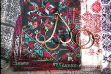 Jpeg 59K Ear rings, bracelets lying on embroidery (possibly for baby carrier pieces) and, to the left, a batik skirt length - Sha Jiao village, Wan Teng township, Xingyi metropolitan area, Guizhou province 0010m15.jpg